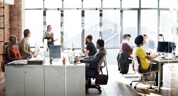 A group of people sitting at tables in front of windows.