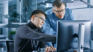 Two men looking at a computer screen.