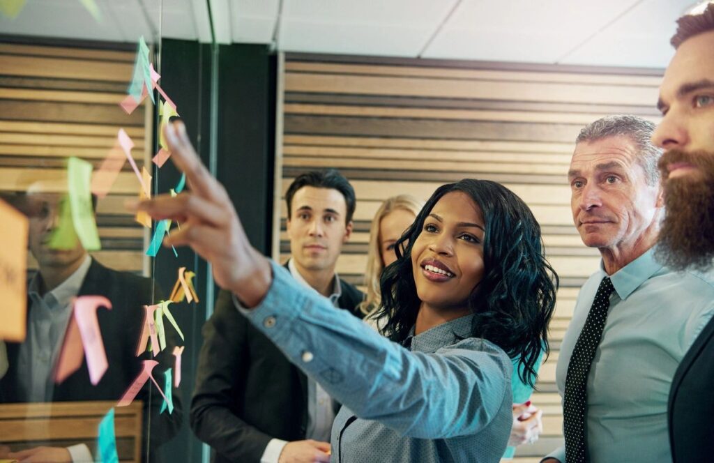 Team brainstorming on glass board.