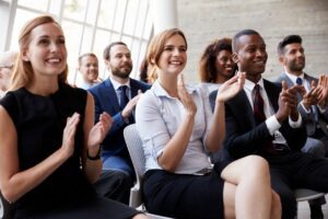 A diverse group of professionals applauding during a meeting.