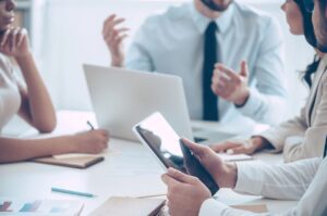 People in a business meeting using digital devices and discussing.