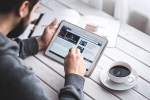 Person using a tablet with a stylus at a desk with coffee.