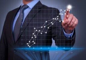 Businessman pointing at upward trending graph.